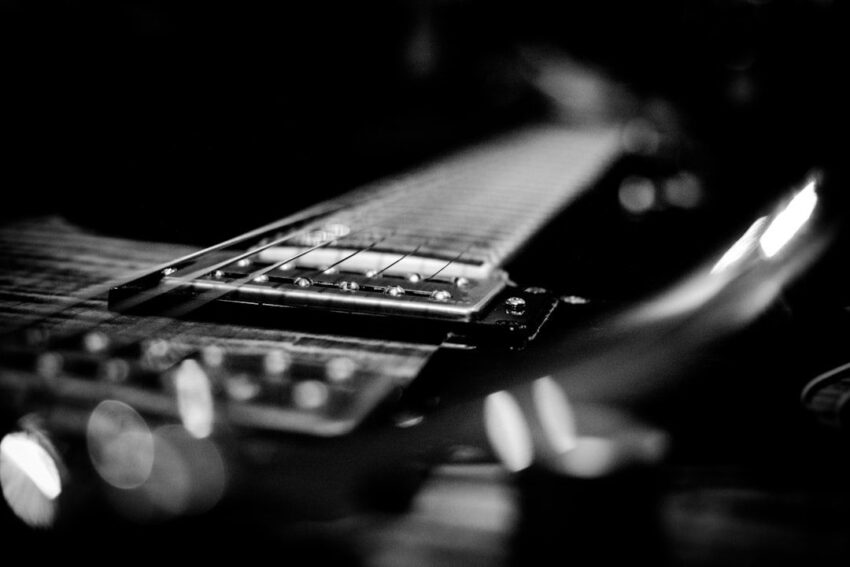 Zwart-wit close-up van de snaren en hals van een elektrische gitaar